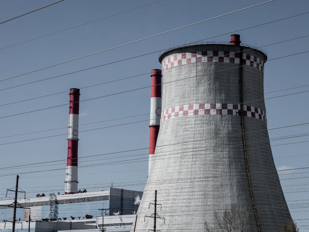 Usina termelétrica com torres de resfriamento e chaminés vermelhas e brancas, utilizada para geração de energia a partir de calor.