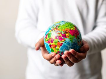 Pessoa segurando um globo terrestre nas mãos, simbolizando responsabilidade individual e mudanças na rotina para cuidar do planeta e promover sustentabilidade.