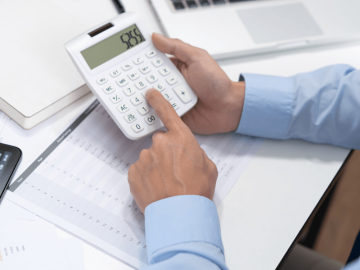 Homem sentando, usando a calculadora e analisando relatórios